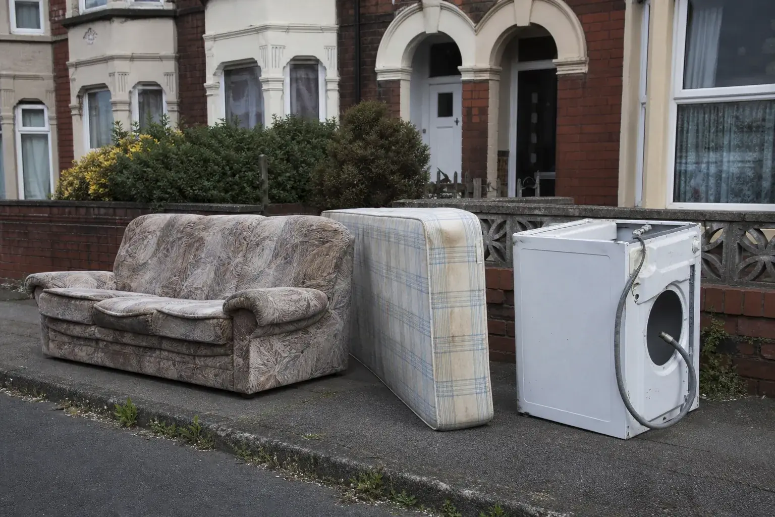 A sofa, mattress and old washing machine set out on a pavement awaiting bulky waste collection